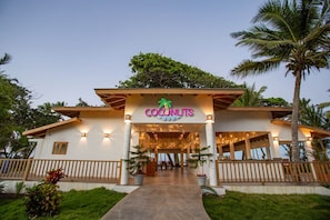 A hotel entrance with a 'Coconuts' sign, a covered walkway, and palm trees. - Tan Villas & Country Club (Sosúa)