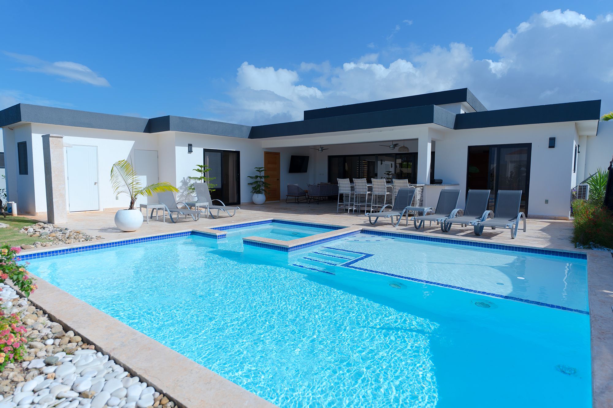 A modern pool area with multiple lounge chairs and a clear blue pool.