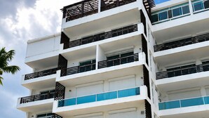 Un edificio de varios pisos con balcones, una escalera y sombrillas de exterior.
