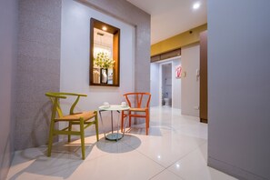Un couloir au design intérieur moderne, comprenant une table ronde avec deux chaises, un miroir et un vase rempli de fleurs.