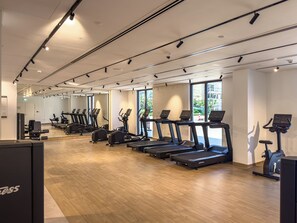 Un gimnasio con cintas de correr, elípticas y un muro de espejos.