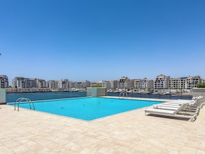 A rooftop swimming pool with lounge chairs, a clear view of the marina, and surrounding buildings. - New Spacious Family 3BR + Kids Room with Sea View (Dubai)