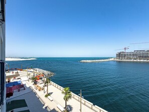 A waterfront view with a pier, a building under construction, and a clear blue sky. - New Spacious Family 3BR + Kids Room with Sea View (Dubai)