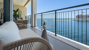 Un balcon avec vue sur la mer, un canapé, une table avec un vase et une plante en pot.