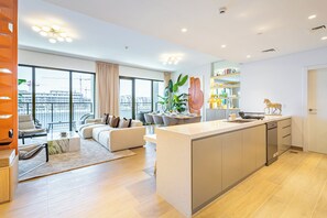 Eine moderne Wohnung mit einer großen Kücheninsel, einem Essbereich und einem Wohnzimmer mit Sofa und Sesseln.