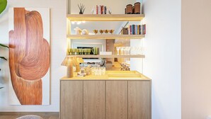 Un intérieur moderne avec un meuble en bois, une étagère remplie de livres et d’objets décoratifs, et un grand tableau abstrait.