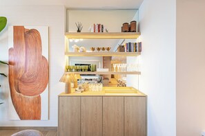 Ein modernes Interieur mit einem Holzkabinett, einem Regal mit Büchern und Dekorationsgegenständen sowie einem großen abstrakten Gemälde.