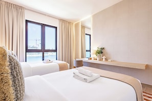 A hotel room with two beds, a large window with curtains, a bedside table with a lamp, and a view of a construction site. - New Spacious Family 3BR + Kids Room with Sea View (Dubai)