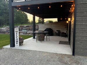 An outdoor patio area with a welcome sign, a barbecue grill, and seating arrangements.