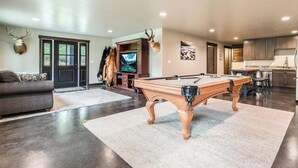 Una sala de estar moderna con mesa de billar, un sofá y una televisión.