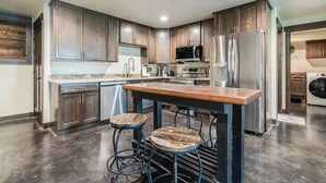 Una cocina moderna con armarios de madera oscura, electrodomésticos de acero inoxidable y una isla central con taburetes.