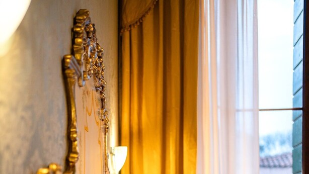 En seng med gavl, lampe og gardiner.