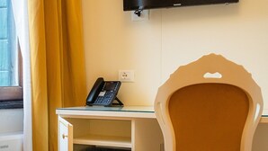 Et værelse med skrivebord, stol, fjernsyn og telefon.