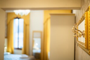 Ein Eingang mit einem goldenen, verzierten Griff, der in einen Raum mit einem Bett und einem Fenster führt.