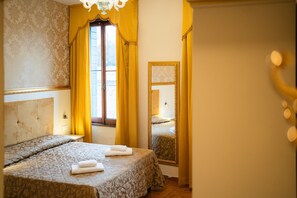 Ein Hotelzimmer mit Bett, einem Vorhangfenster, einem Spiegel und einer Kristallleuchter.