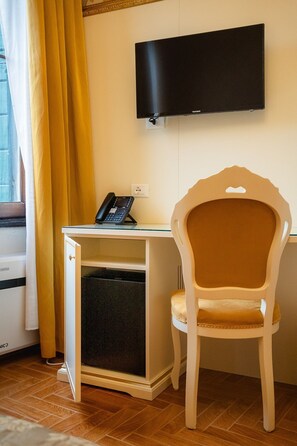 Ein Zimmer mit Schreibtisch, Stuhl, Fernseher und Telefon.