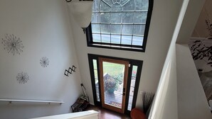 A staircase leading to a second-floor landing with a large arched window, a white wall with decorative elements, and a wooden floor. - Cozy 1-bedroom in a spacious house with AC in charming Powder Springs (Powder Springs)