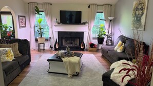 A living room with a fireplace, sofas, a coffee table, and a TV. - Cozy 1-bedroom in a spacious house with AC in charming Powder Springs (Powder Springs)