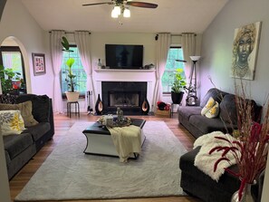 A living room with a fireplace, sofas, a coffee table, and a TV. - Cozy 1-bedroom in a spacious house with AC in charming Powder Springs (Powder Springs)