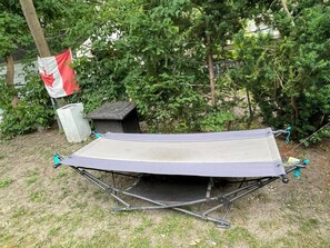 A hammock set up outdoors with a Canadian flag, surrounded by trees and a small structure. - Little slice of heaven n heart of Toronto. (Toronto)