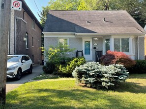 A residential house with a garage, a front yard with a lawn, and a driveway. - Little slice of heaven n heart of Toronto. (Toronto)