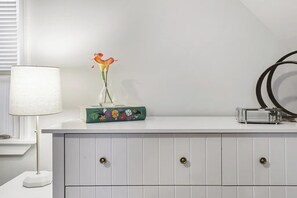 A white dresser with a vase of flowers, a lamp, and a decorative box. - Spacious 4-bedroom house - St. Charles with AC (St. Charles)