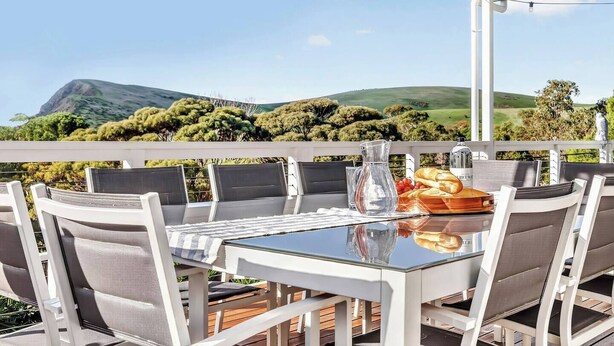 A table with chairs, a pitcher, glasses, and a bread basket on a balcony with a view of hills and trees. - The Ark Beachside Sanctuary with Valley Views (Second Valley)