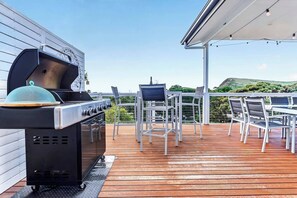 Eine Terrasse im Freien mit Grill, Stühlen und Tisch.