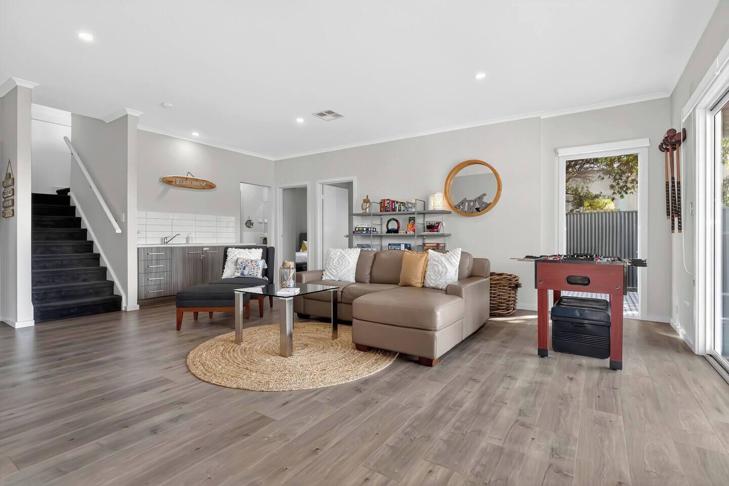 A modern living room with a sofa, coffee table, and a foosball table.