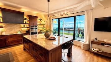 A modern kitchen with a large island, wooden cabinets, and a view of the marina.