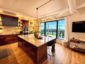Eine moderne Küche mit einer großen Kochinsel, Holzschränken und Blick auf den Yachthafen.