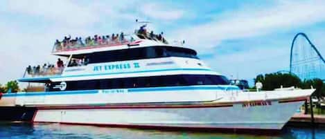 A large white yacht with "JET EXPRESS II" written on the side, docked at a pier with a roller coaster in the background.