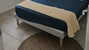 Ein Schlafzimmer mit einem Bett, einem Nachttisch, einer Lampe und zwei gerahmten Pflanzenbildern an der Wand.
