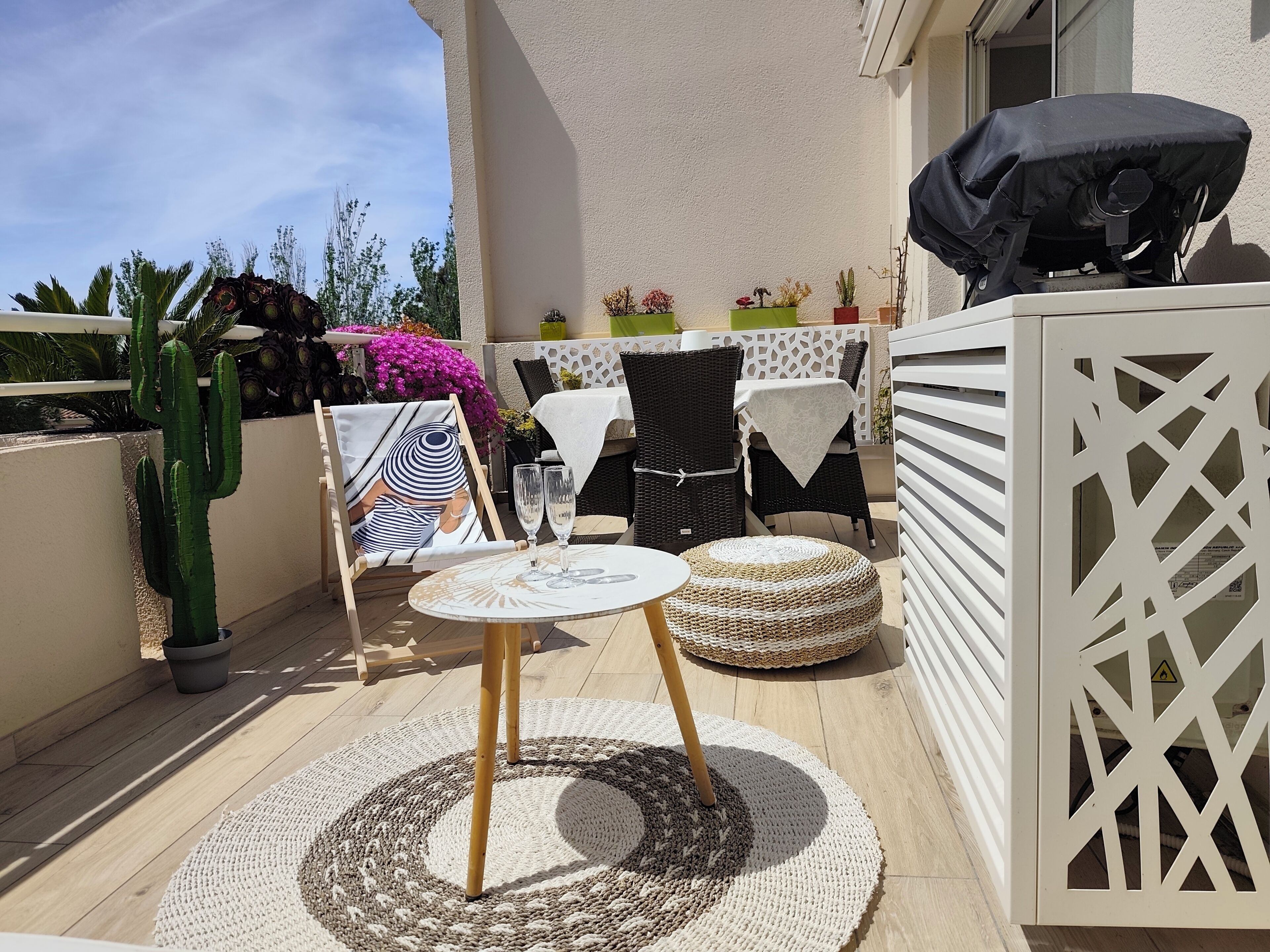 A patio with a round table, chairs, and a small rug.