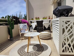 Eine Terrasse mit rundem Tisch, Stühlen und einem kleinen Teppich.