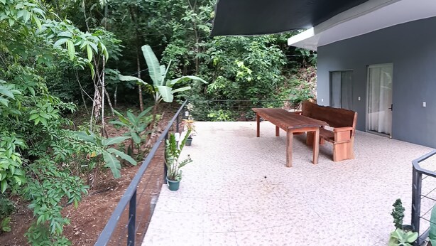 A modern building with a balcony, a wooden table and bench, and surrounding greenery. - CASA MONO: Peace and Adventure (Pavones)