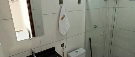 Ein Badezimmer mit Duschkabine, weißer Toilette und schwarzem Waschbecken.