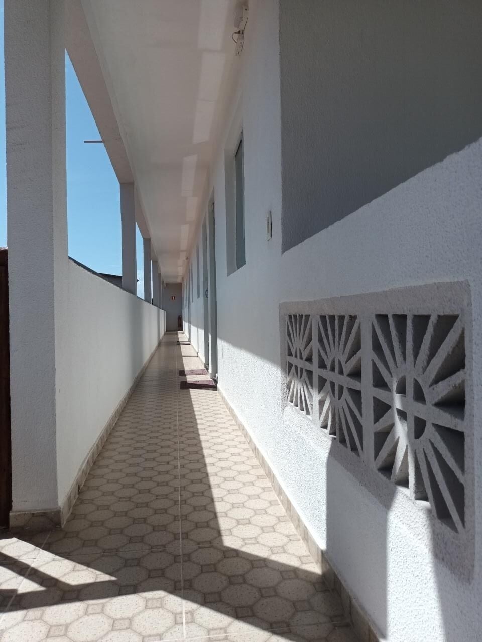 A corridor with hexagonal patterned flooring, white walls, and decorative panels.
