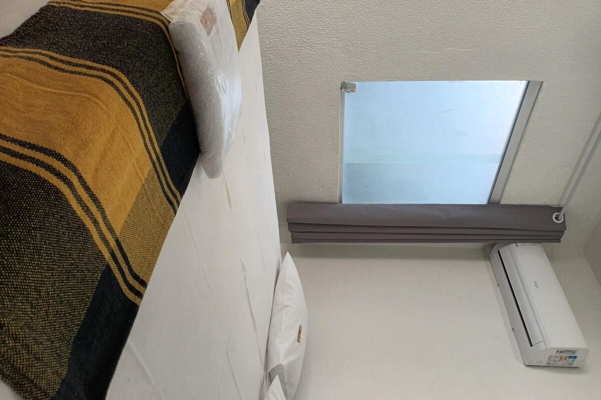 Una habitación con cama, tragaluz y aire acondicionado.