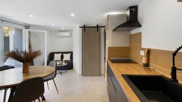 A modern kitchen with a black sink, wooden countertop, and a black range hood.