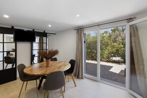 Ein stilvoller Essbereich mit Holztisch, grauen Stühlen und einem großen Fenster mit Vorhängen.