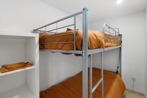 Un lit superposé avec une étagère en dessous et une prise électrique sur le mur.