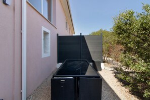 Un bâtiment doté d’un grand portail noir, d’une fenêtre et d’un chemin de gravier menant à un arbre.