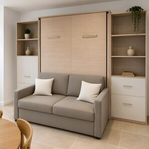 A modern living room with a sofa, a coffee table, a dining table, and a cabinet with shelves. - Studio Apartment 'Villa Laurent' with Private Garden and Wi-Fi (Solaro)