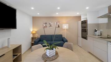 Una sala moderna con un sofá, una mesa de centro con una planta y un televisor de pantalla plana montado en la pared.