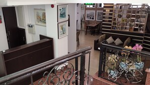 A hotel lobby with a staircase, a reception desk, framed artwork on the walls, and a seating area with a sofa and decorative items. - Tbiliseli Inn (Tbilisi)