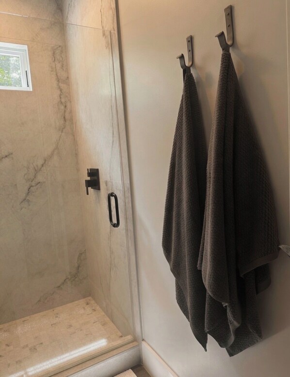 Ein Badezimmer mit Dusche, einem Handtuchhalter mit zwei Handtüchern und einer Tür mit Griff.