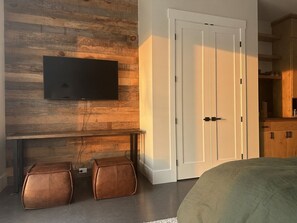 A room with a mounted television, a white door, and a wooden wall.