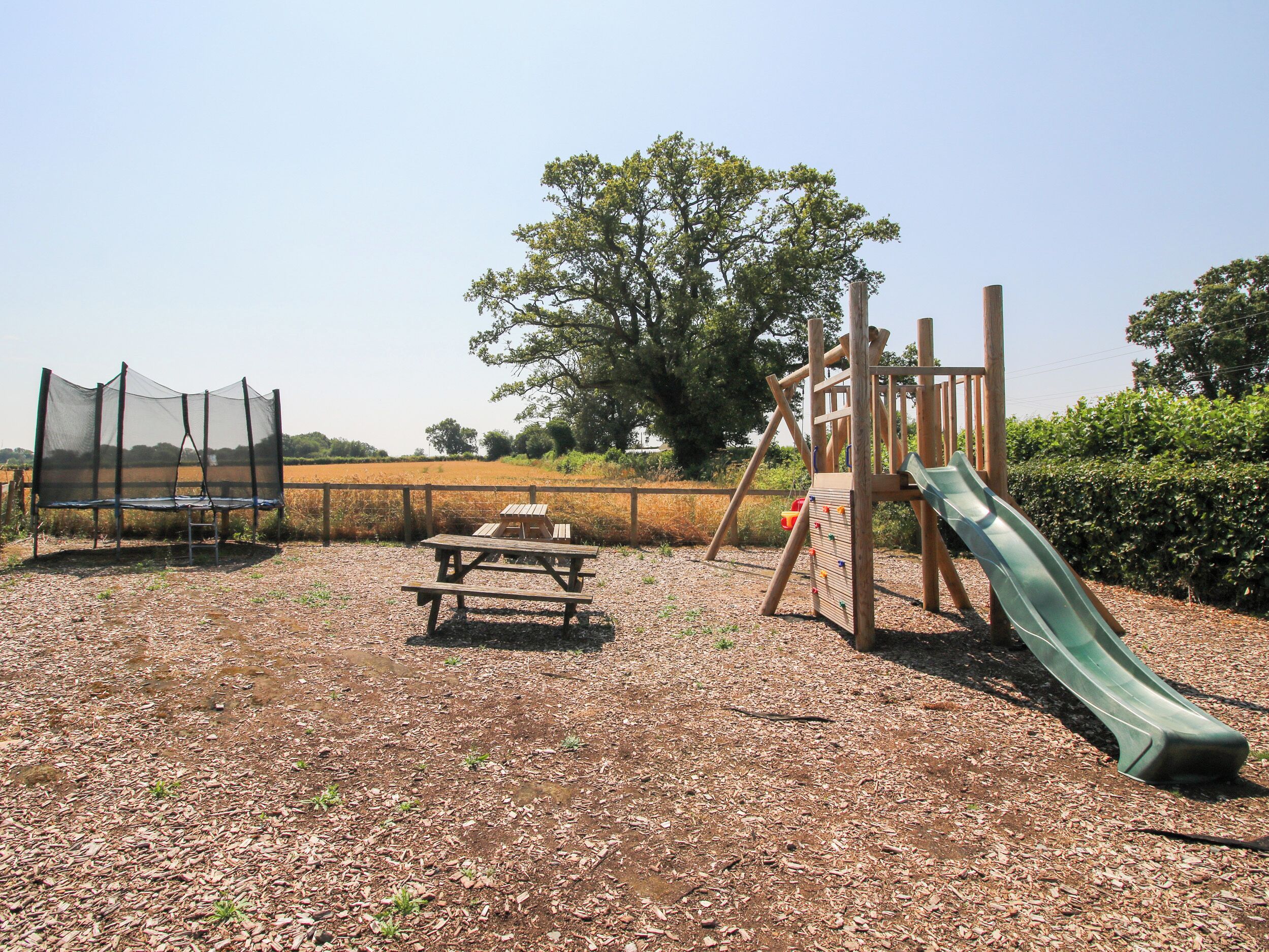 Ein Spielplatz mit Rutsche, Schaukel und Trampolin.