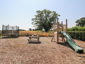 Ein Spielplatz mit Rutsche, Schaukel und Trampolin.